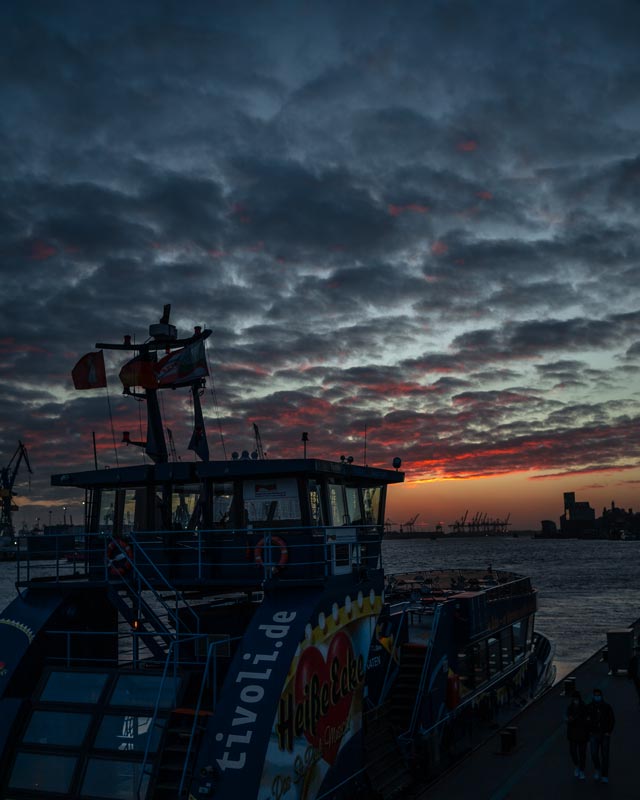 Sonnenuntergang am Hamburger Hafen mit einer Fähre im Vordergrund